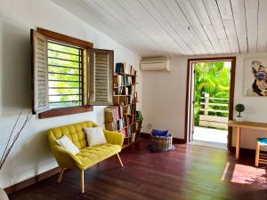 a living room with a yellow couch and a book shelf at La Voile Grise - Villa de charme - Sea View in Le Gosier