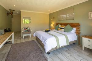 a bedroom with a large white bed and a chair at Garden View Studio in Plettenberg Bay