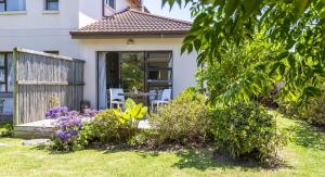 a house with a garden with purple flowers at Garden View Studio in Plettenberg Bay