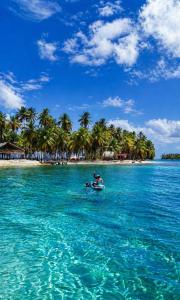 a person on a boat in the water near an island at camping eco demar achu in Cayos Los Grullos +4 photos