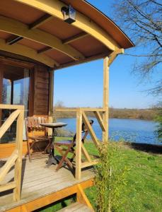 a cabin with a deck with a table and a view at La Roulotte du Marais in Éclusier-Vaux