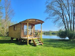 a tiny house sitting in the grass next to a lake at La Roulotte du Marais in Éclusier-Vaux +23 photos