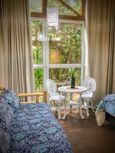 a bedroom with a table and chairs and a window at Suites Guarda do Embau in Palhoça