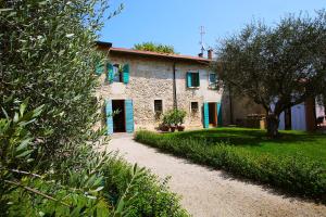 a stone house with green shutters and a driveway at Cascina Girolda in Peschiera del Garda