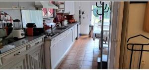 a kitchen with white cabinets and a tile floor at Ptit Piment petite maison avec terrasse in Lanton