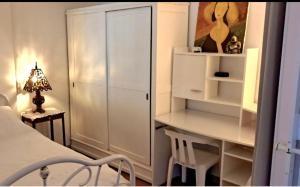 a bedroom with a white cabinet and a desk at Ptit Piment petite maison avec terrasse in Lanton