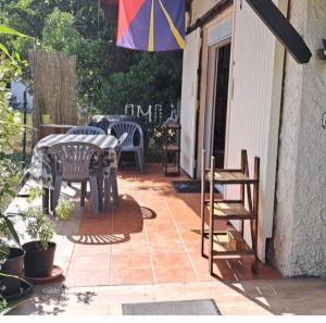 a patio with a table and chairs and an umbrella at Ptit Piment petite maison avec terrasse in Lanton