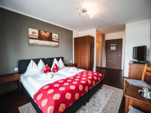 a hotel room with a bed with a red blanket at Faaker See Inn by Aurora in Faak am See