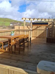 a wooden deck with a wooden table and benches at Hillhouse Coastal Escapes - PODs in Donegal +13 photos
