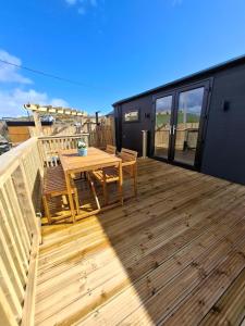 a wooden deck with a wooden table and chairs at Hillhouse Coastal Escapes - PODs in Donegal
