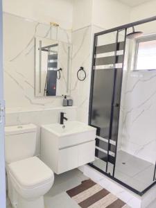 a white bathroom with a toilet and a shower at Stella Maris 123 in Amanzimtoti +26 photos
