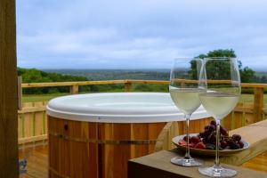 two glasses of wine sitting on a table next to a tub at Coldharbour Cottage with Hot Tub in Stone +23 photos