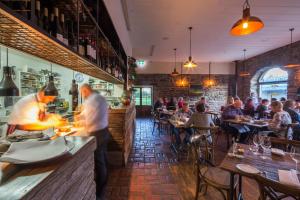 un ristorante con chef che prepara i pasti in un bar di Olivers Central Otago a Clyde