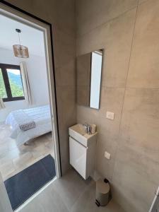 a bathroom with a sink and a bed and a mirror at appartement olivese in Olivese