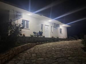 a man sitting on the porch of a white house at night at Damiano House in Sarandë