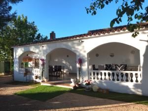 a white house with a porch and a table at Rustic Chalet With Easy Golf Beach Access Oliva Nova in Oliva