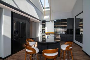 a kitchen with a black island and wooden chairs at Slotvin Apartments in Słotwiny