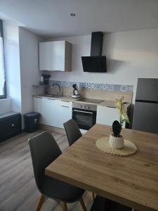 a kitchen with a wooden table with chairs and a dining room at L Arcluzette in Fréterive +6 photos