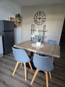 a dining room table with two blue chairs and a clock at L Arcluzette in Fréterive