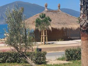 a hut with a straw roof and a palm tree at Elite Sunset Residence in Vlorë +10 photos