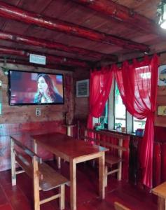 a dining room with a table and a tv and red curtains at The Temple, Laguna de la Cocha in El Encano
