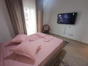 a bedroom with a bed with pink sheets and a flat screen tv at Ryhane in El Haouach