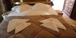 a bed with white pillows on top of it at Ζachlorou Inn in Kalavrita
