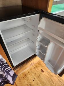 an empty refrigerator with its door open on a wooden floor at Orange Lake Airstream in Whiting