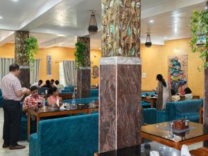 a group of people sitting at tables in a restaurant at Dip Holidays Resort in Shānti Niketan