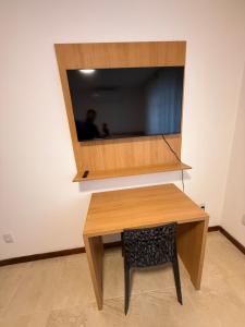 a wooden desk with a television on a wall at Casa da Dinda 202 in Rio das Ostras