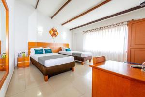 a bedroom with two beds and a desk at Hotel Optimum in Pereira