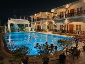 a swimming pool in front of a building at night at Dip Holidays Resort in Shānti Niketan