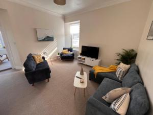 a living room with two couches and a tv at Vistamar Dunoon in Dunoon