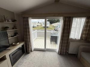 a living room with a sliding glass door to a deck at Modern Seton Sands Caravan - sleeps 6 in Port Seton +2 photos