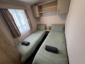 two beds in a small room with a window at Modern Seton Sands Caravan - sleeps 6 in Port Seton