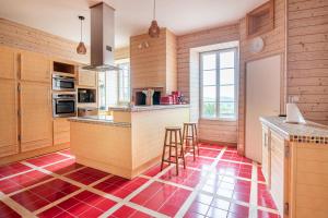 a kitchen with wooden cabinets and a red floor at Gîte de l'Esplanade-18 min du Puy du Foù-Ventilateurs- Billard- Baby-foot-Fléchettes-Grande maison de bourg spacieuse de 200m2- Famille-Amis-Groupe in Pouzauges