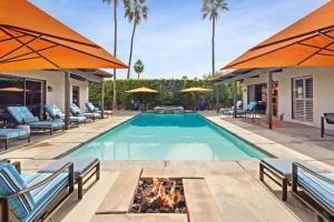 an outdoor swimming pool with chairs and a fire pit at Desert Solstice in Palm Springs