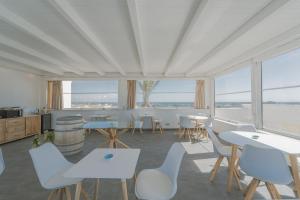 a room with tables and white chairs and windows at Ponente & Maestro Rooms in Favignana +38 photos