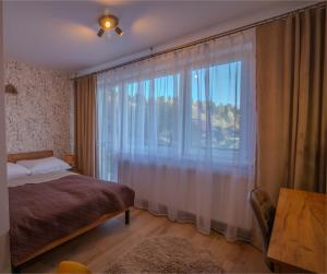 a bedroom with a bed and a large window at Apartamenty Sielska 102 in Szlachtowa