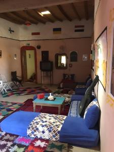 a living room with blue couches and a table at Merzouga Hostel in Merzouga