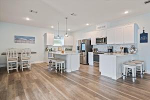 a kitchen with white cabinets and bar stools at Let's get Beachy! in Bolivar Peninsula