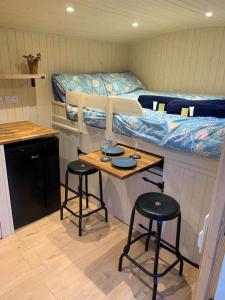a room with two tables and two bunk beds at Heated shepherds hut overlooking open countryside in Chichester