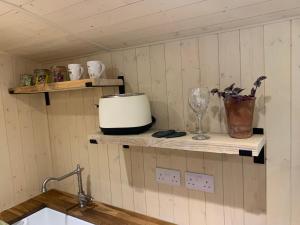 a kitchen with wooden shelves with a toaster and a sink at Heated shepherds hut overlooking open countryside in Chichester