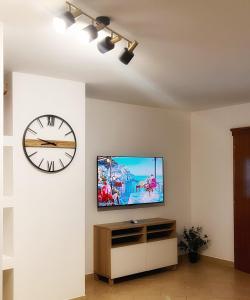 a room with a tv and a clock on the wall at Apartman Ćosić in Kruševica