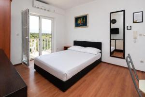 a bedroom with a large bed and a balcony at Apartments Peris Resort in Novalja