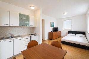 a bedroom with a bed and a kitchen with a table at Apartments Peris Resort in Novalja