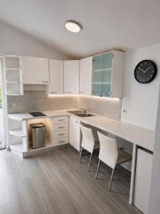 a kitchen with white cabinets and a counter with chairs at Apartments Peris Resort in Novalja