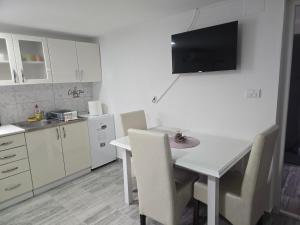 a kitchen with a white table with chairs and a tv on the wall at Studio Villa Ruža in Golubac