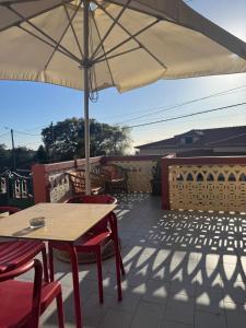 a patio with a table and chairs and an umbrella at Descanso imparcial in Prazeres