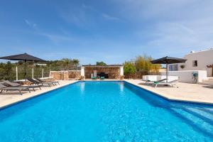 a pool with chairs and umbrellas next to a house at New! Villa Plana Menut in Santa Gertrudis de Fruitera